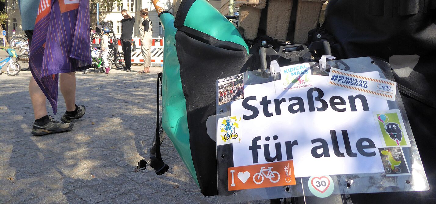 Kidical Mass Schöneberg: Straßen für alle! Auf einem Schild, das am Gespäckträger eines Fahrrads hängt, steht "Straßen für alle".