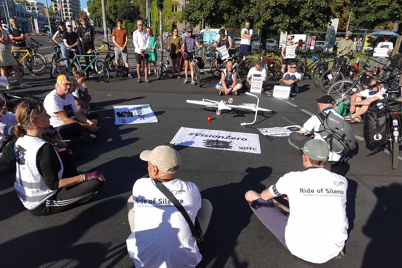 Menschen sitzen bei einer Mahnwache für eine getötete Radfahrerin auf der Straße