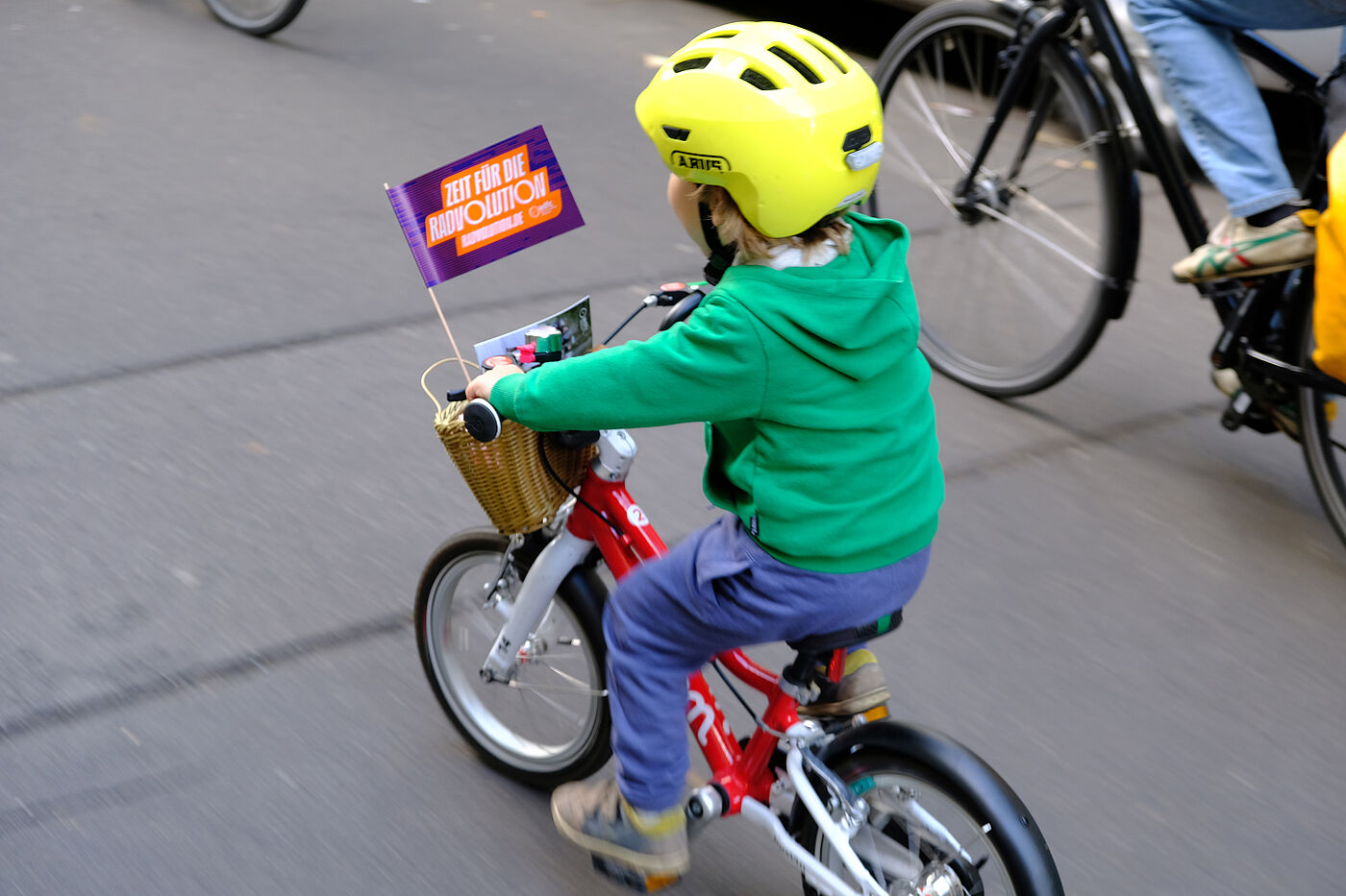 Kidical Mass Fhain 09-2023 Kind mit gelbem Helm auf Fahrrad mit RADvolution Fähnchen