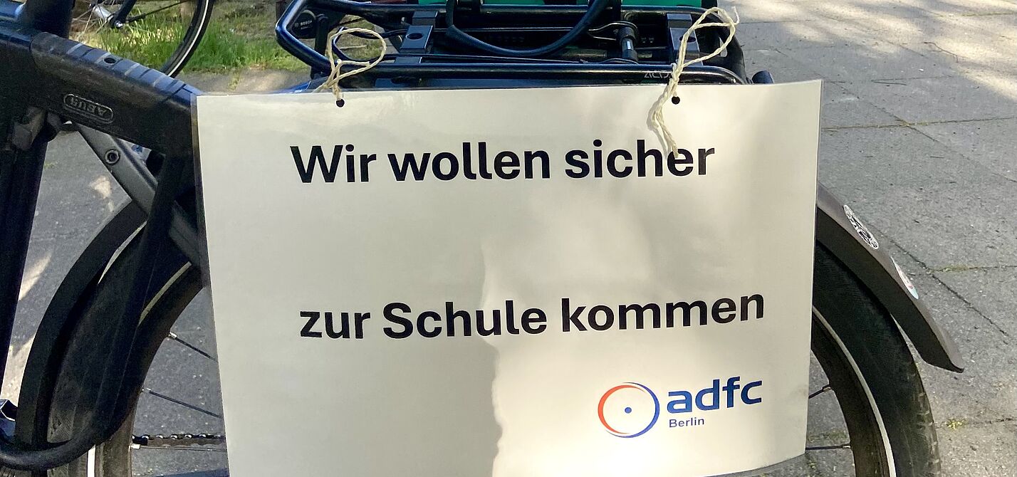 Auf einem Schild des ADFC Berlin für eine Fahrraddemo auf der Marienfelder Allee steht: "Wir wollen sicher zur Schule kommen"