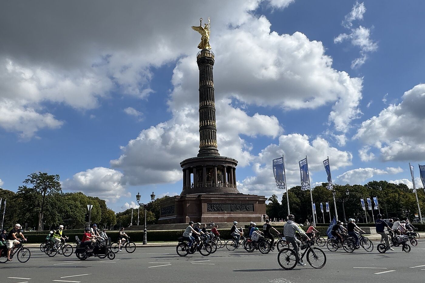 Großer STern Vor der Siegessäule fahren Radfahrende.