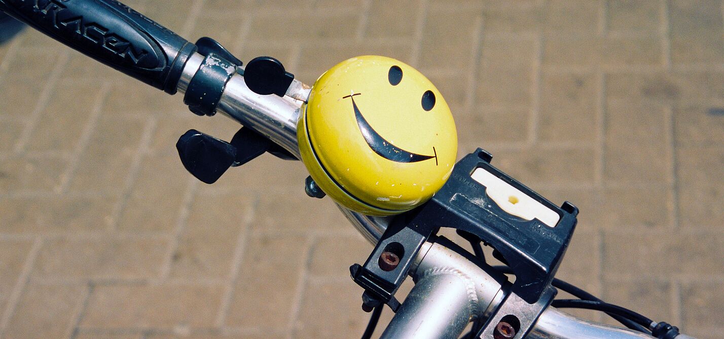 Smiley-Fahrradklingel an einem Fahrradlenker.
