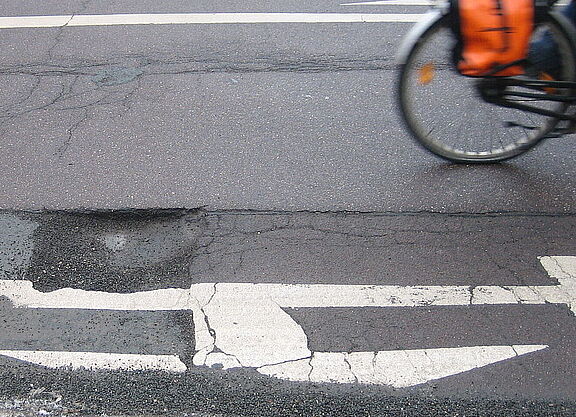 Schlagloch auf der Straße Ein Schlagloch auf der Straße, man sieht noch das Hinterrad eines vorbeifahrenden Fahrrads.