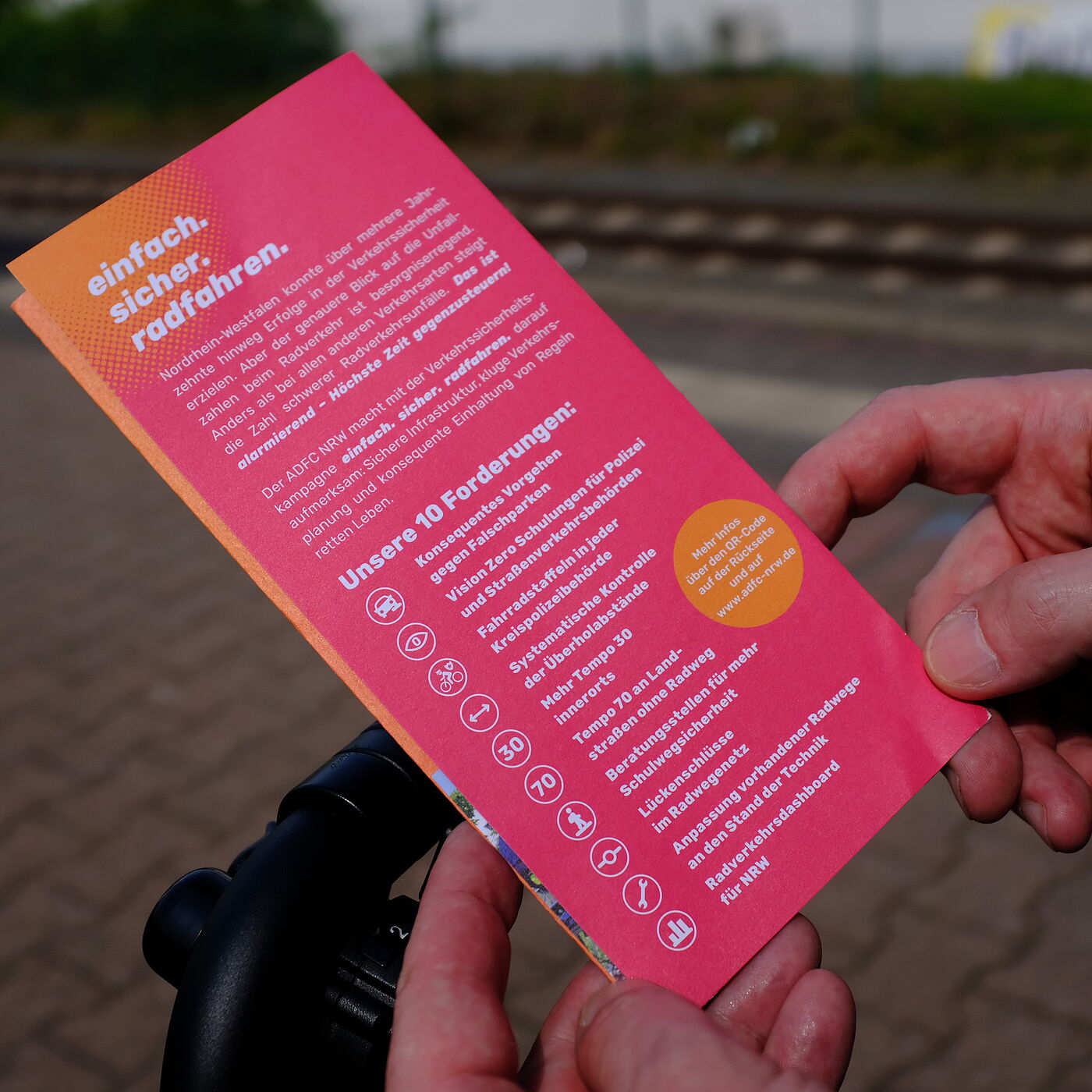 2026-04-17_Dormagen_Verkehrssicherheit__ADFC_NRW Eine Person hält einen Flyer in den Händen.