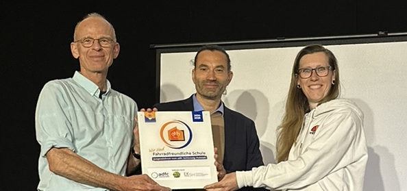 Übergabe Plakette "Fahrradfreundliche Schule" Nora Müller (links) vom ADFC SH übergibt die Plakette "Fahrradfreundliche Schule" an Mathias Kadow-Leder (Schulleiter Holstenschule) und Christian Wagner (Fahrradbeauftrager Holstenschule Neumünster)
