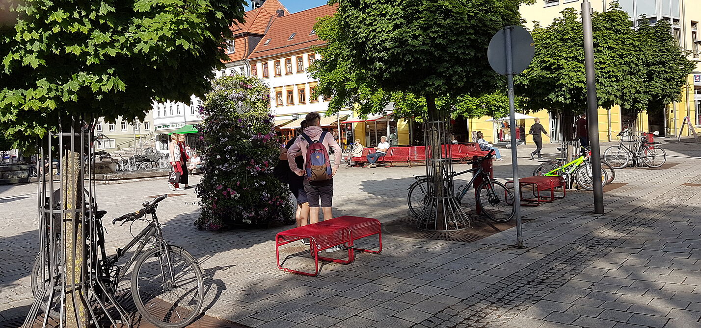 Fahrräder stehen an Baumschutzgittern in Suhl, im Hintergrund der Dianabrunnen