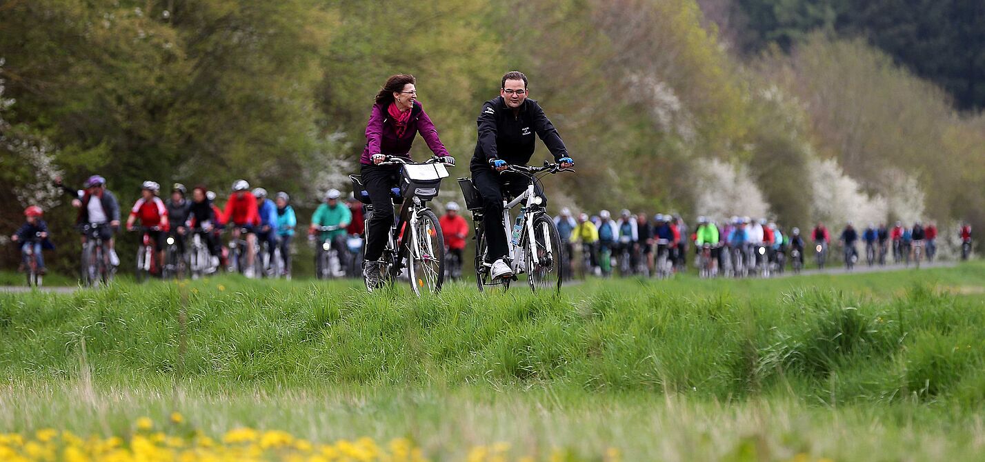 Anradeln im Rodachtal Zu sehen ist eine Gruppe Radfahrern, im Vordergrund Blumenwiese und im Hintergrund Bäume