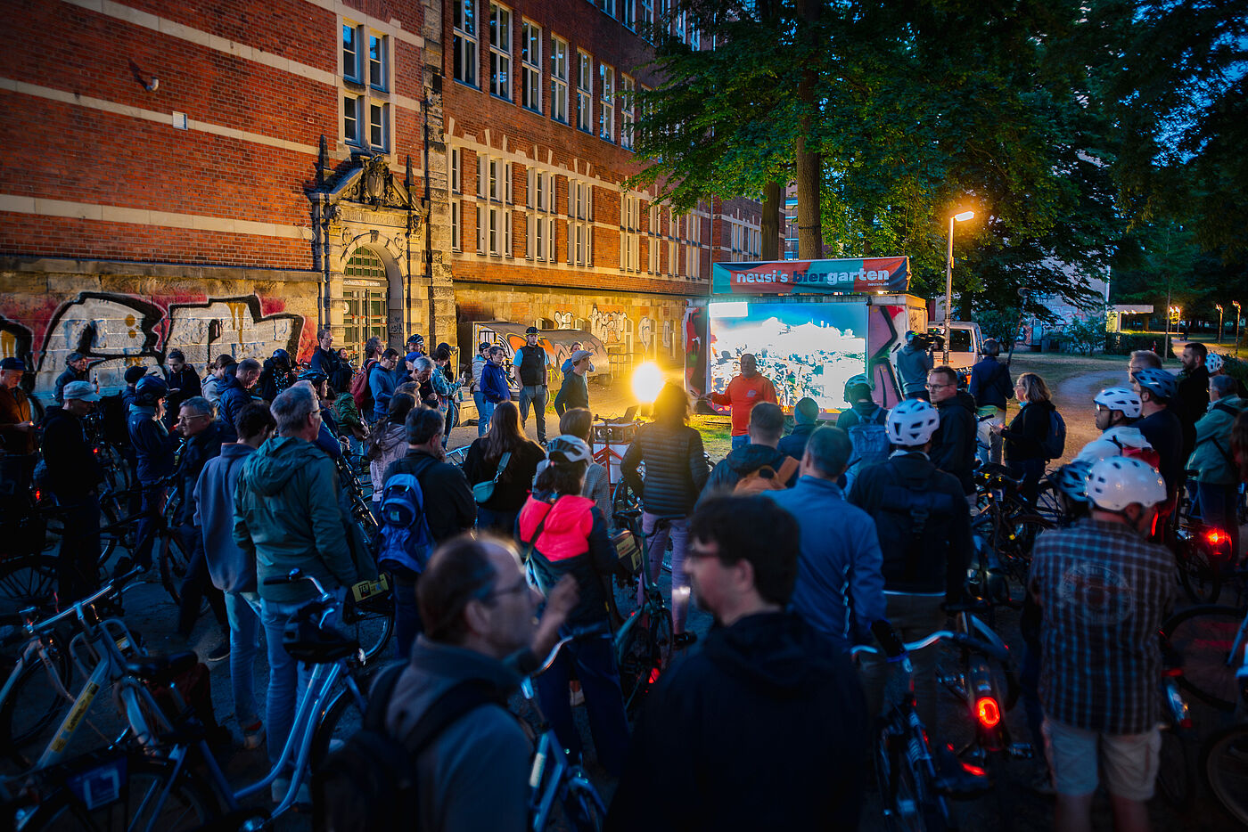 Radfahrende vor kleiner Filmleinwand bei Nacht