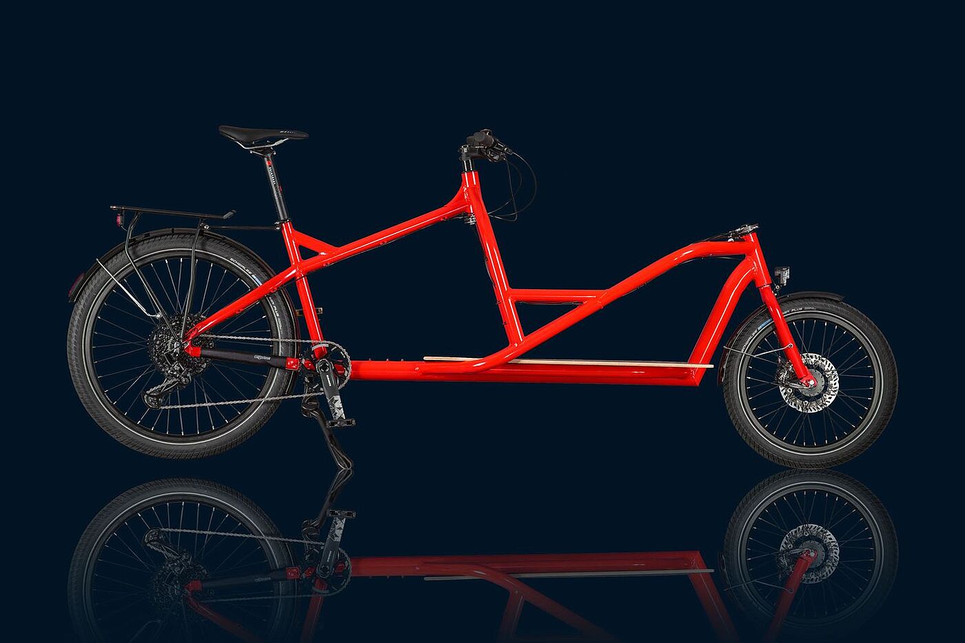 Ein rotes Lastenrad vor schearzem Hintergrund. 