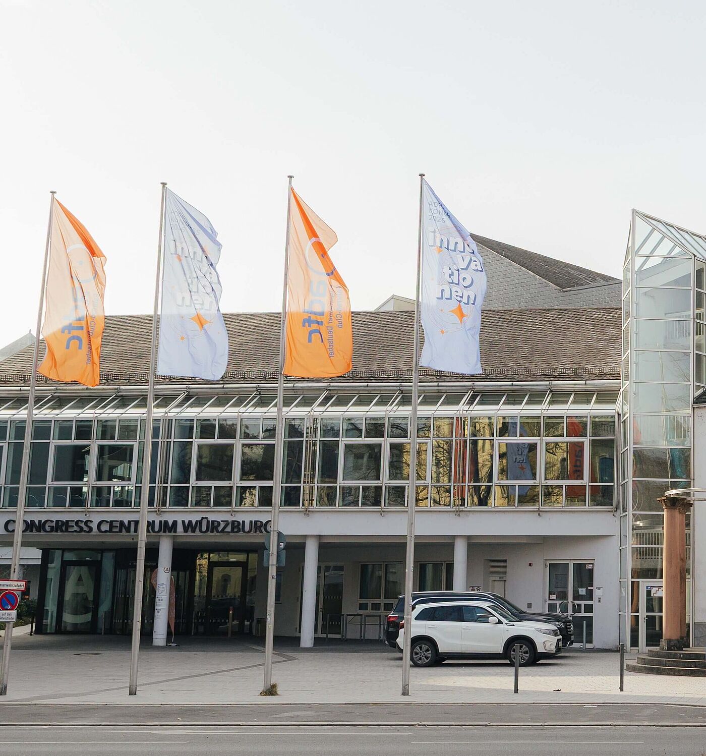 Ansicht des Congress Centrum Würzburg mit vielen bunten Fahnen vor dem Gebäude an einer Straße, darunter ADFC-Fahnen.