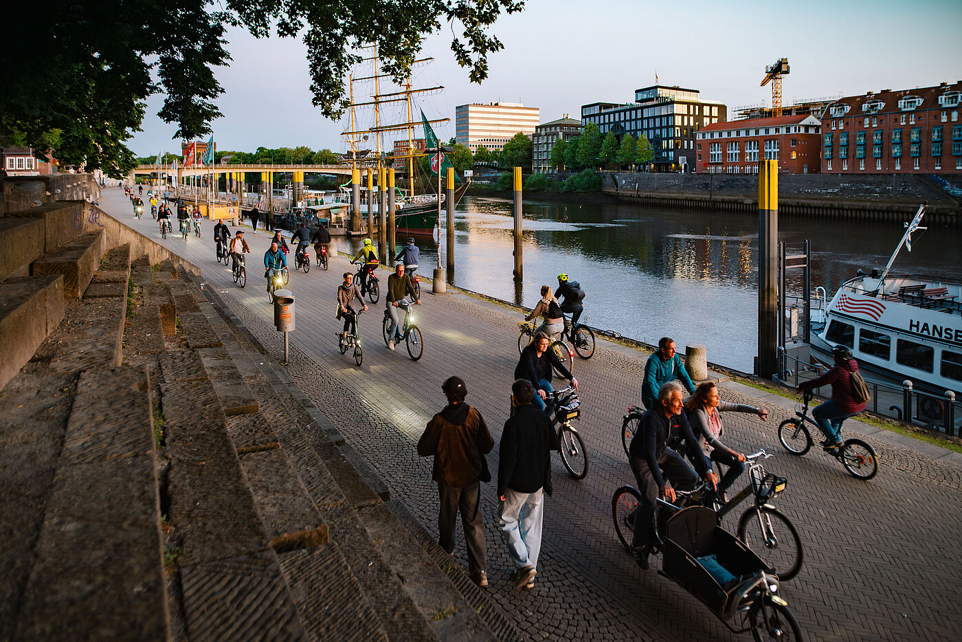 Menschen auf dem Fahrrad am Weserufer beim Sonnenuntergang