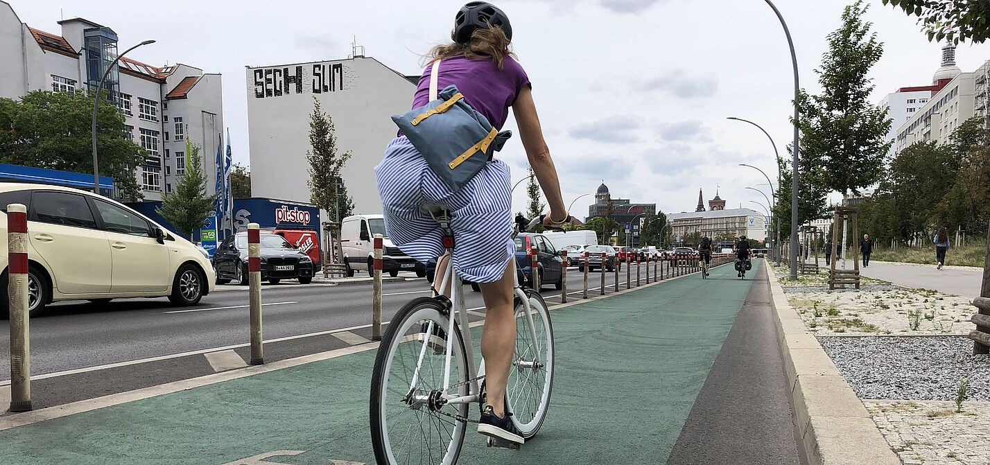 Frau auf geschütztem Radfahrstreifen Frau auf geschütztem Radfahrstreifen