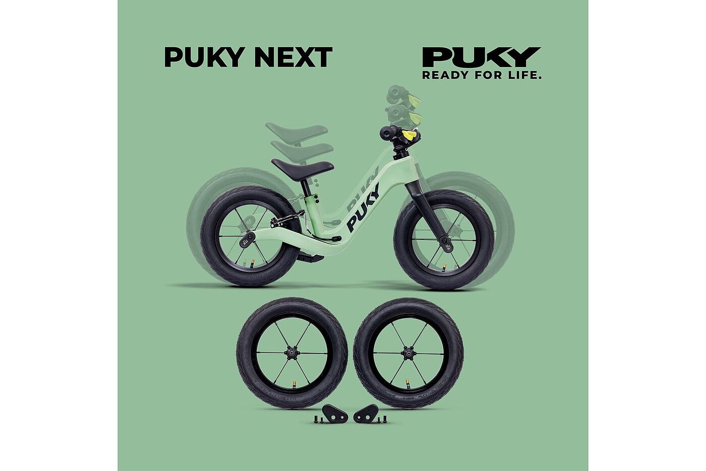 Puky Next 2 Hellgrünes Laufrad mit verstellbarem Sattel, zwei zusätzlichen schwarzen Laufrädern und kleinen Montageteilen vor grünem Hintergrund.