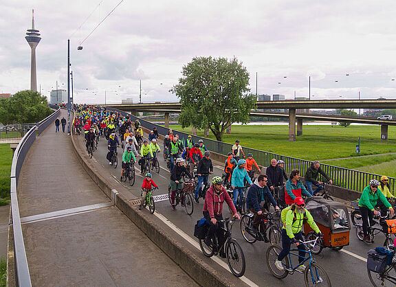 Viele Radfahrende fahren auf einer Brücke.