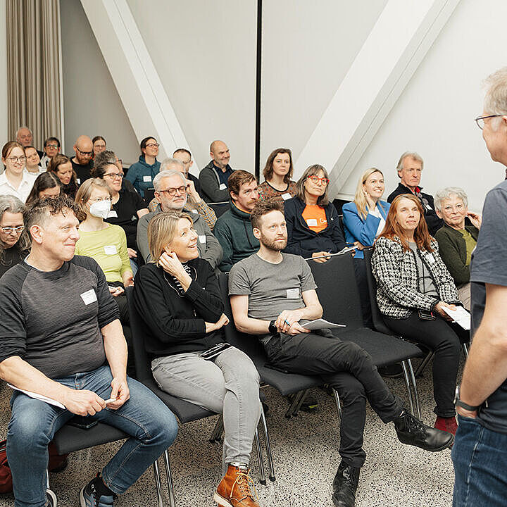 Viele Menschen sitzen in Reihen und hören einer stehenden Person bei einem Vortrag auf dem ADFC Kongress 2026 zu.