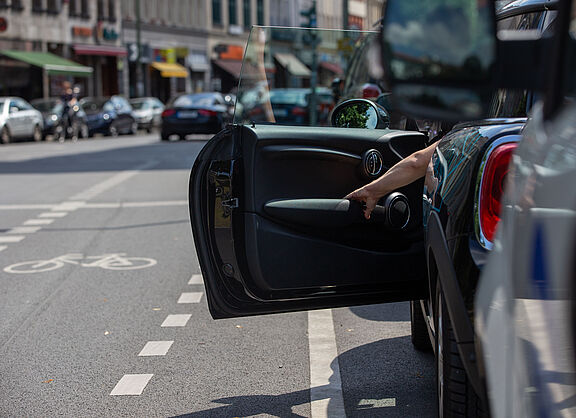 Plötzlich geöffnete Autotür im Straßenverkehr – typische Gefahrensituation für vorbeifahrende Radfahrende.