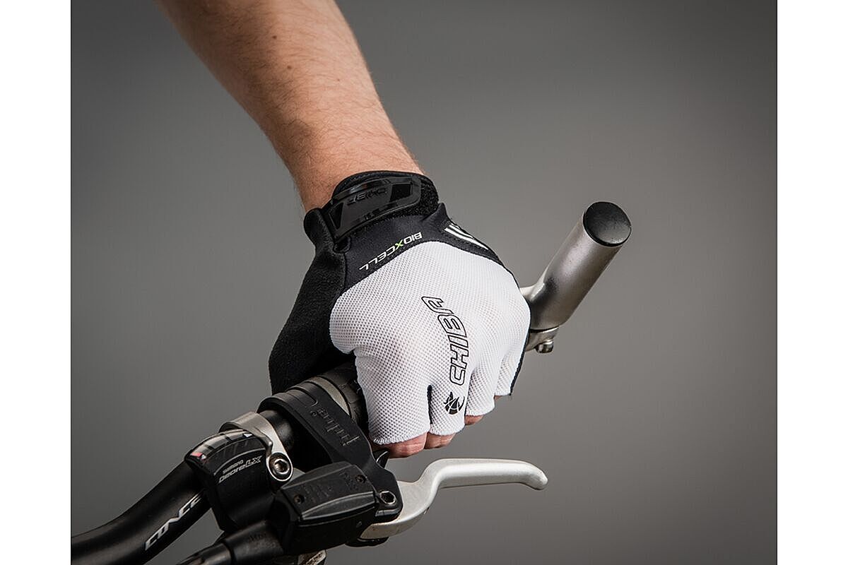 Eine Hand mit weißem Chiba-Handschuh an einem Fahrradlenker. 