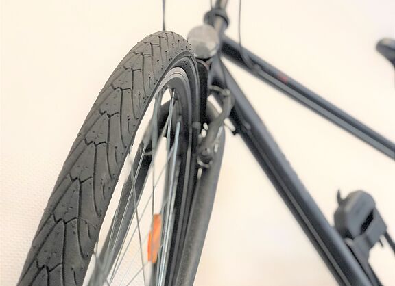 Aufnahme eines Reifens frontal, Fahrrad verschwommen im Hintergrund. 