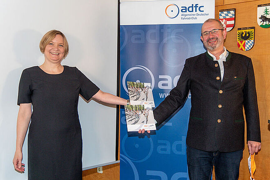 ADFC Bayern 30. Geburtstag Bernadette Felsch und Armin Falkenhein präsentieren vor blauem Hintergrund die Broschüre "30 Jahre ADFC Bayern".