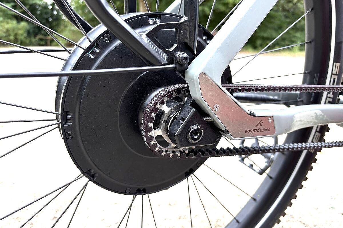 Motor Großaufnahme eines schwarzen Hinterradmotors, davor der Antriebsrimen, an einem grauen Fahrrad.