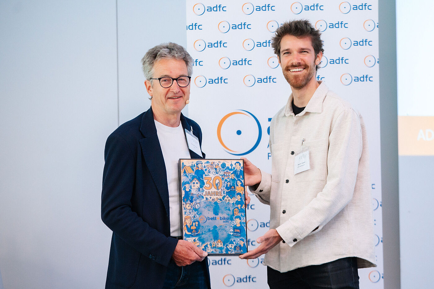 Zwei Personen mit Übergabe einer Urkunde zum Jubiläum