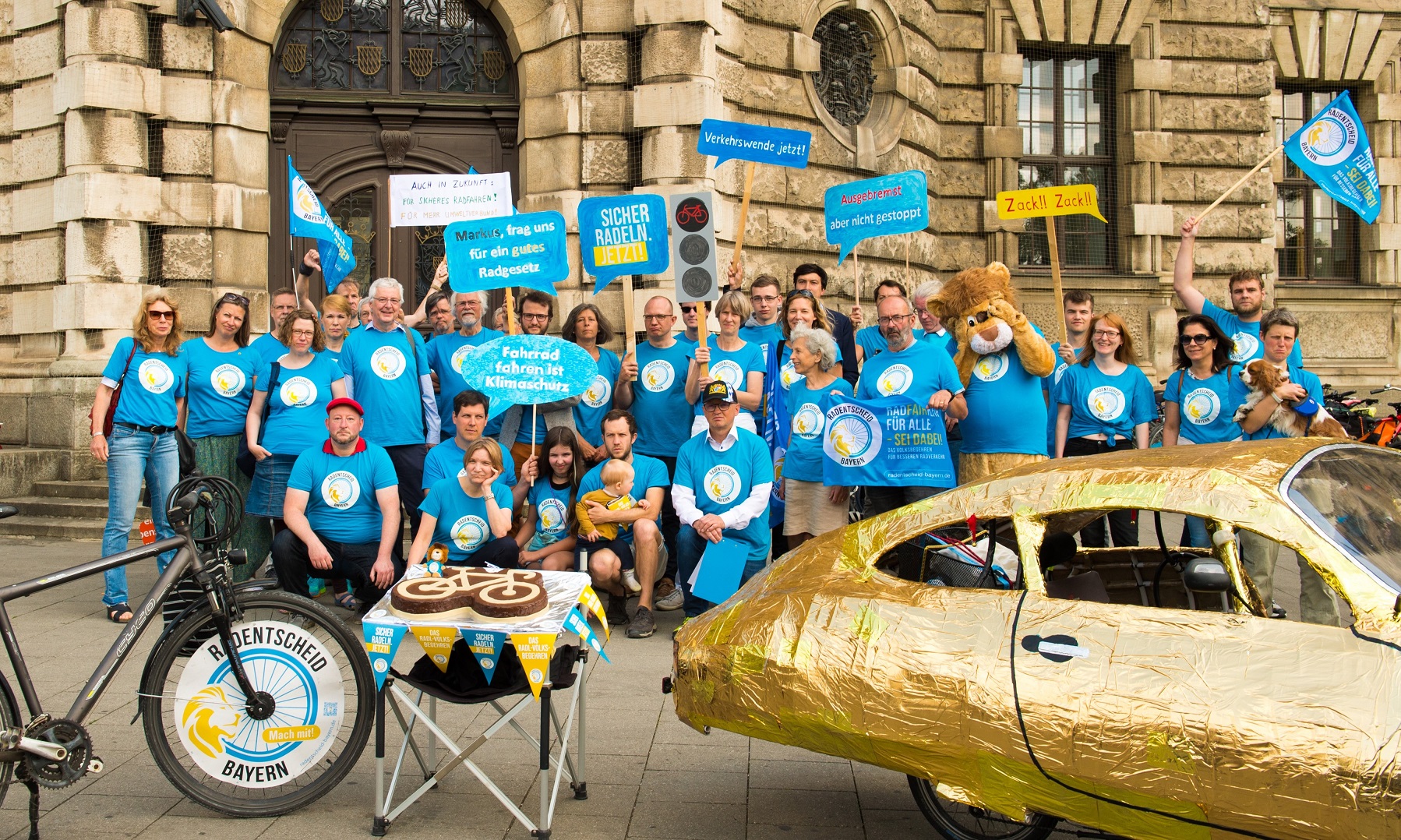 Eine Gruppe Radentscheid-Aktivist:innen vor dem Bayerischen Verfassungsgerichts-Gebäude in blauen T-Shirts. 
