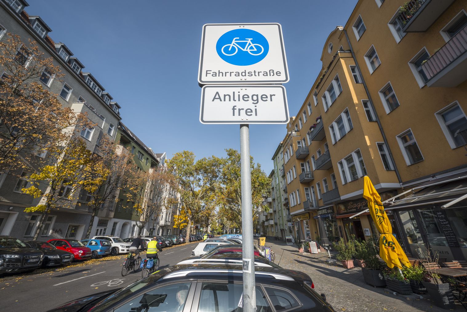 Blick auf ein Verkehrszeichen "Fahrradstraße" am Eingang einer Straße mit Wohnhäusern auf beiden Seiten. 