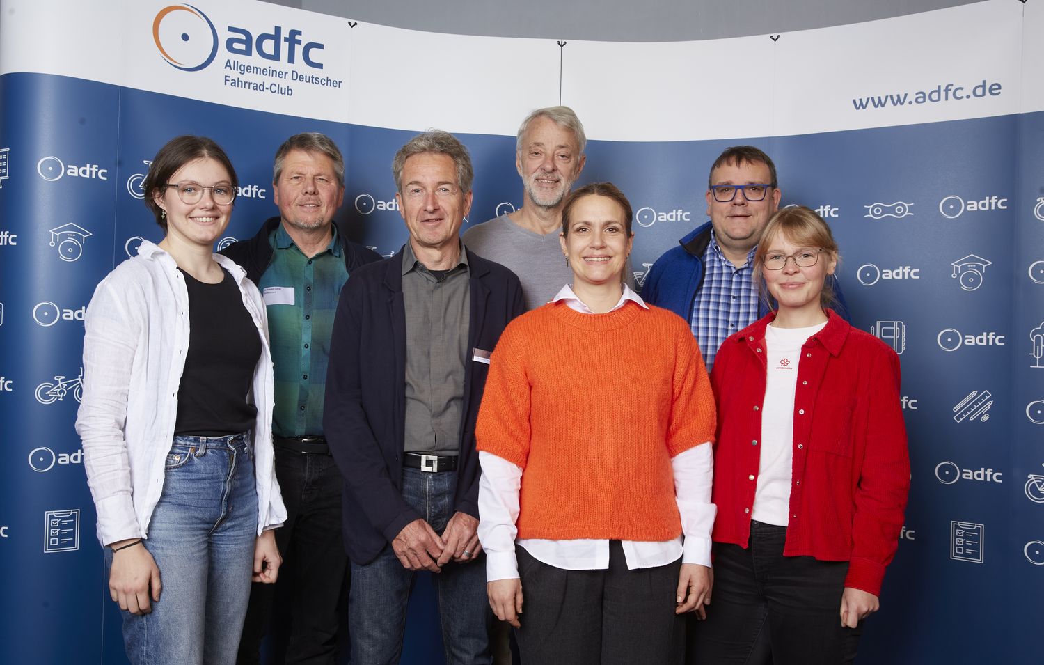 Ein Gruppenbild vor einem blauen Hintergund mit ADFC-Logos. Der neue ADFC-Bundesvorstand. Von links nach rechts: Lena Adam, Joachim Lohse, Christian Tänzler, Frank Masurat, Sarah Holczer, Christoph Schmidt und Vera Konrad. Nicht im Bild: Clara Bohle. 
