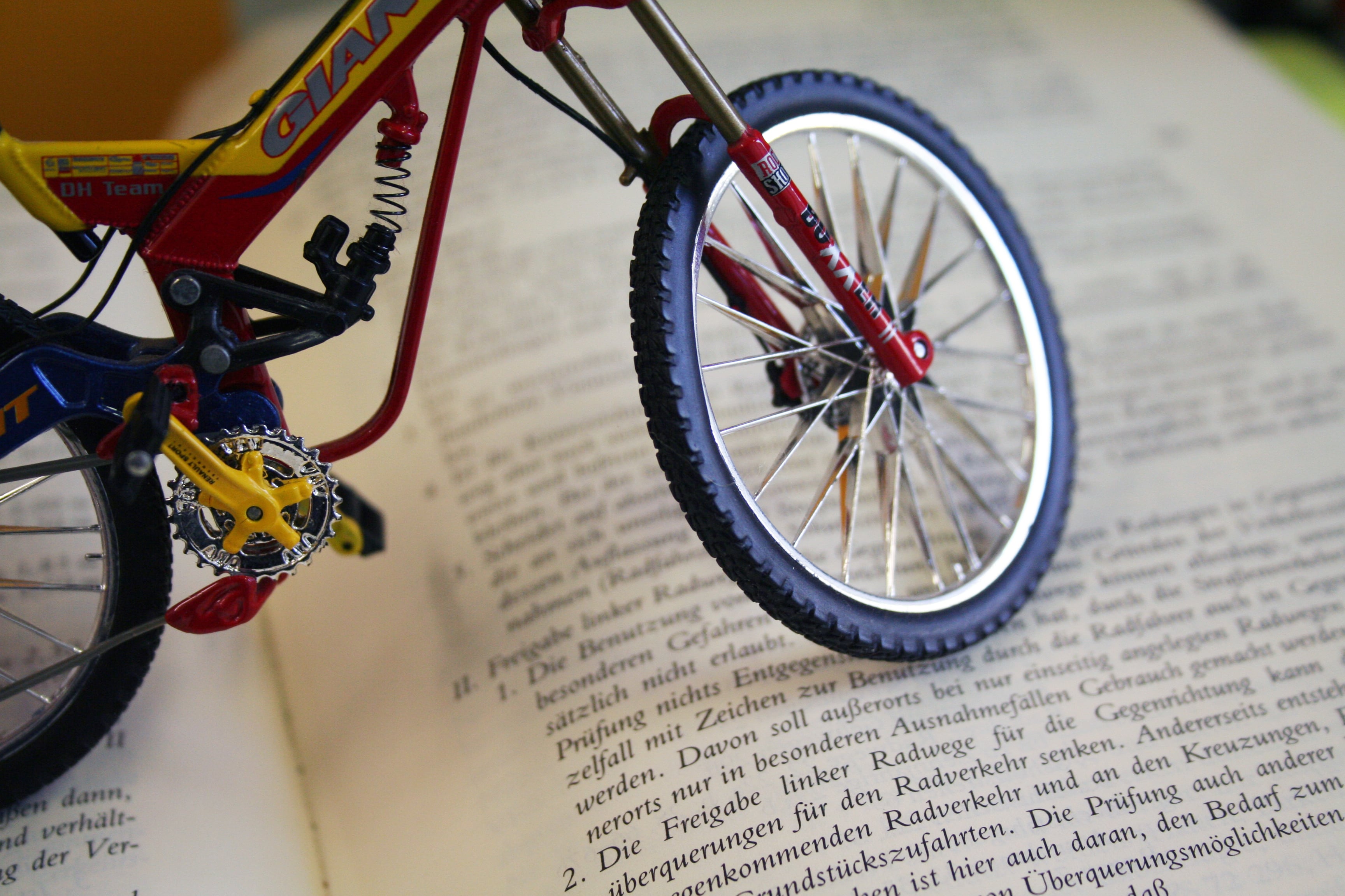 Miniatur-Fahrrad steht auf einem aufgeschlagenen Buch mit deutschem Gesetzestext.