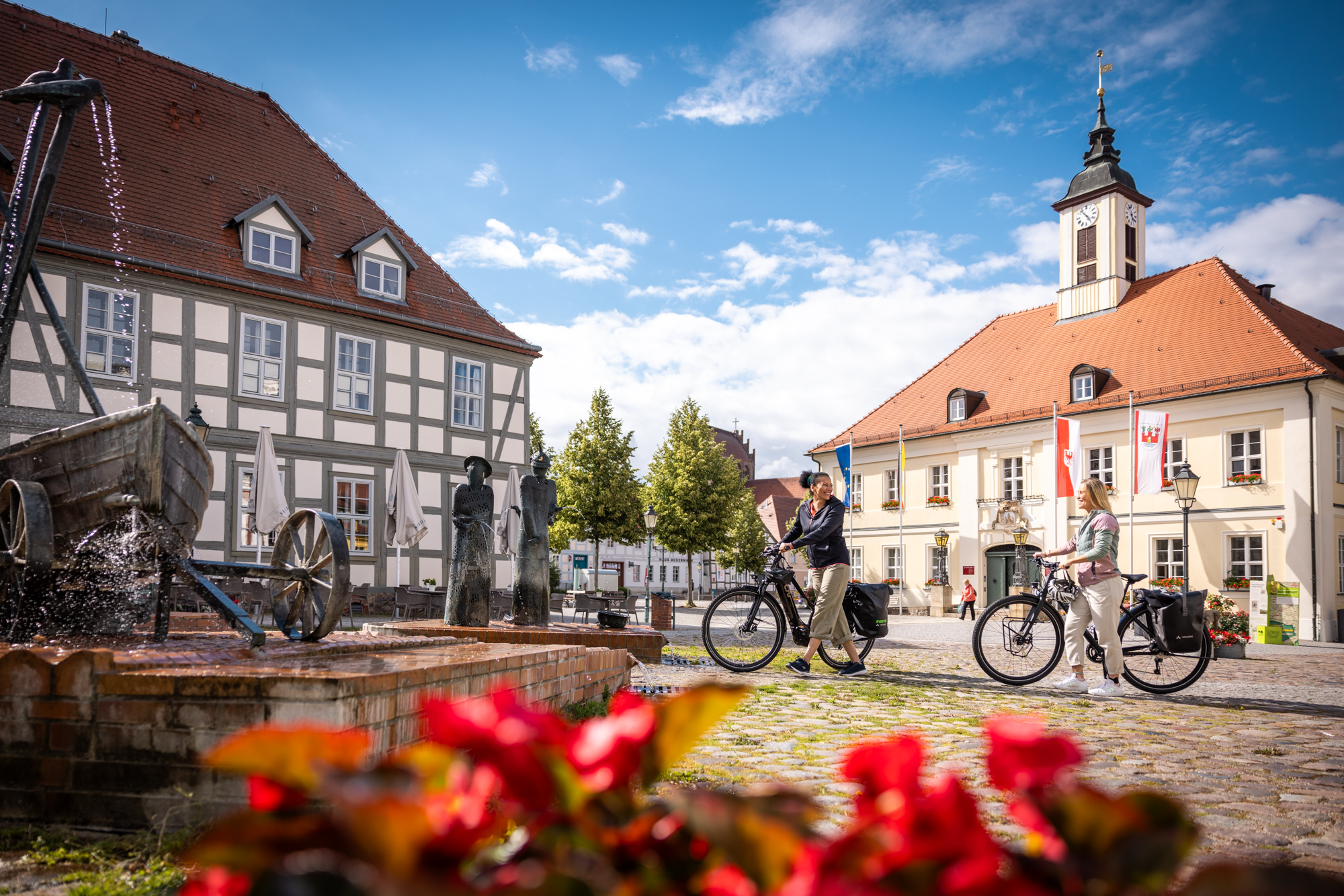Zwei Frauen mit Fahrrädern auf einem kleinen Marktplatz in einer brandenburgischen kleinen Stadt