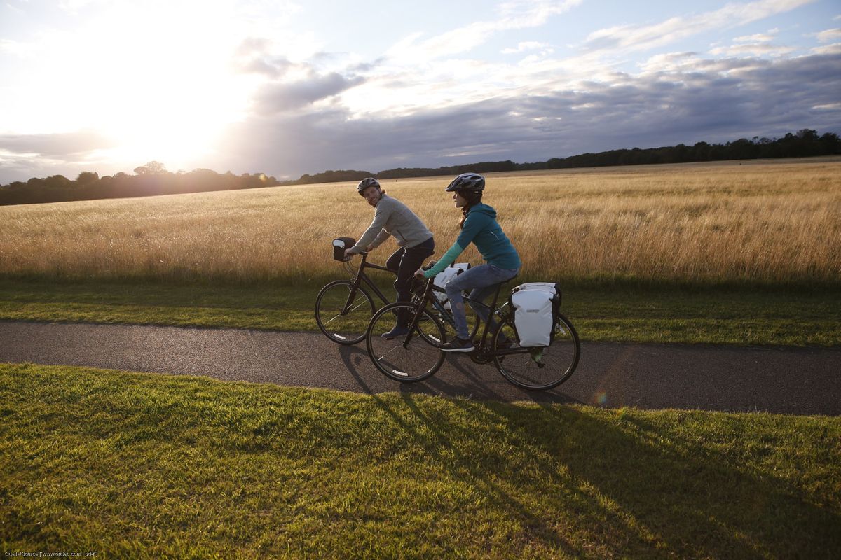 Zwei Radfahrende auf Tour vor herbstlicher Kulisse im Gegenlicht. 
