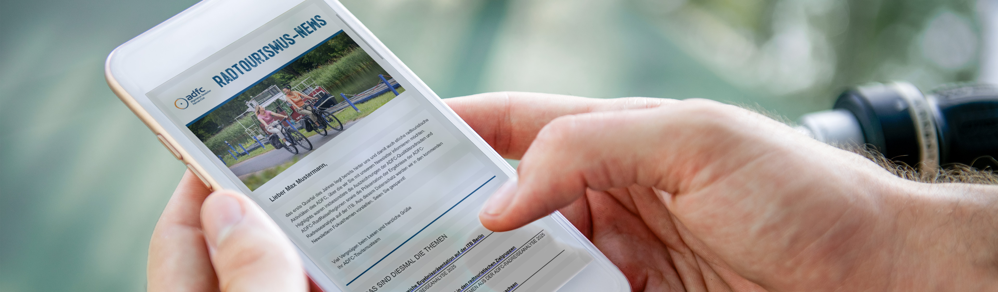 Bildauschnitt mit Händen, die ein Handy halten auf dem der Newsletter zu sehen ist