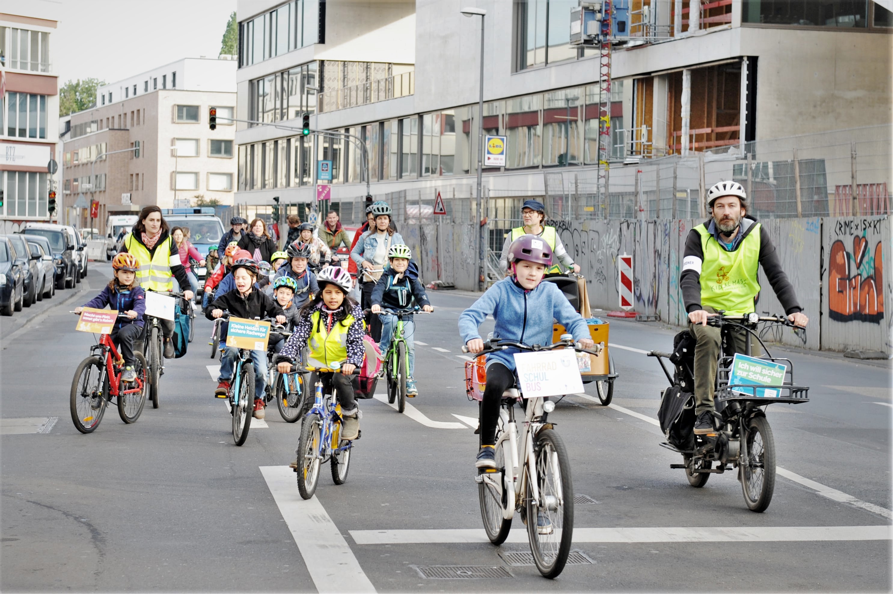 Beim Fahrradbus fahren Kinder und Eltern in der Gruppe auf der Straße.