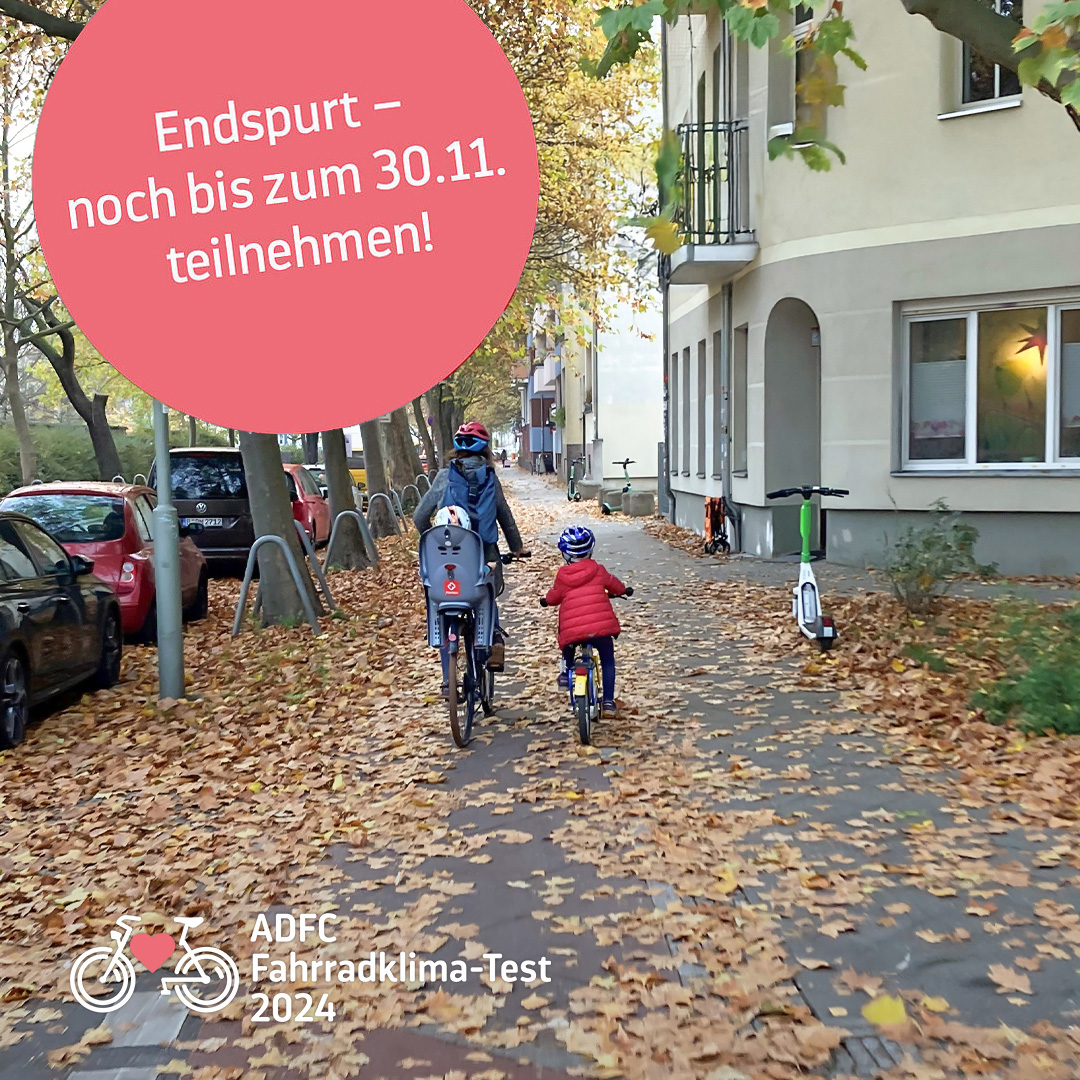 Eine Mutter und ihre Kinder fahren auf einem herbstlich mit Blättern gesäumten Gehweg.
