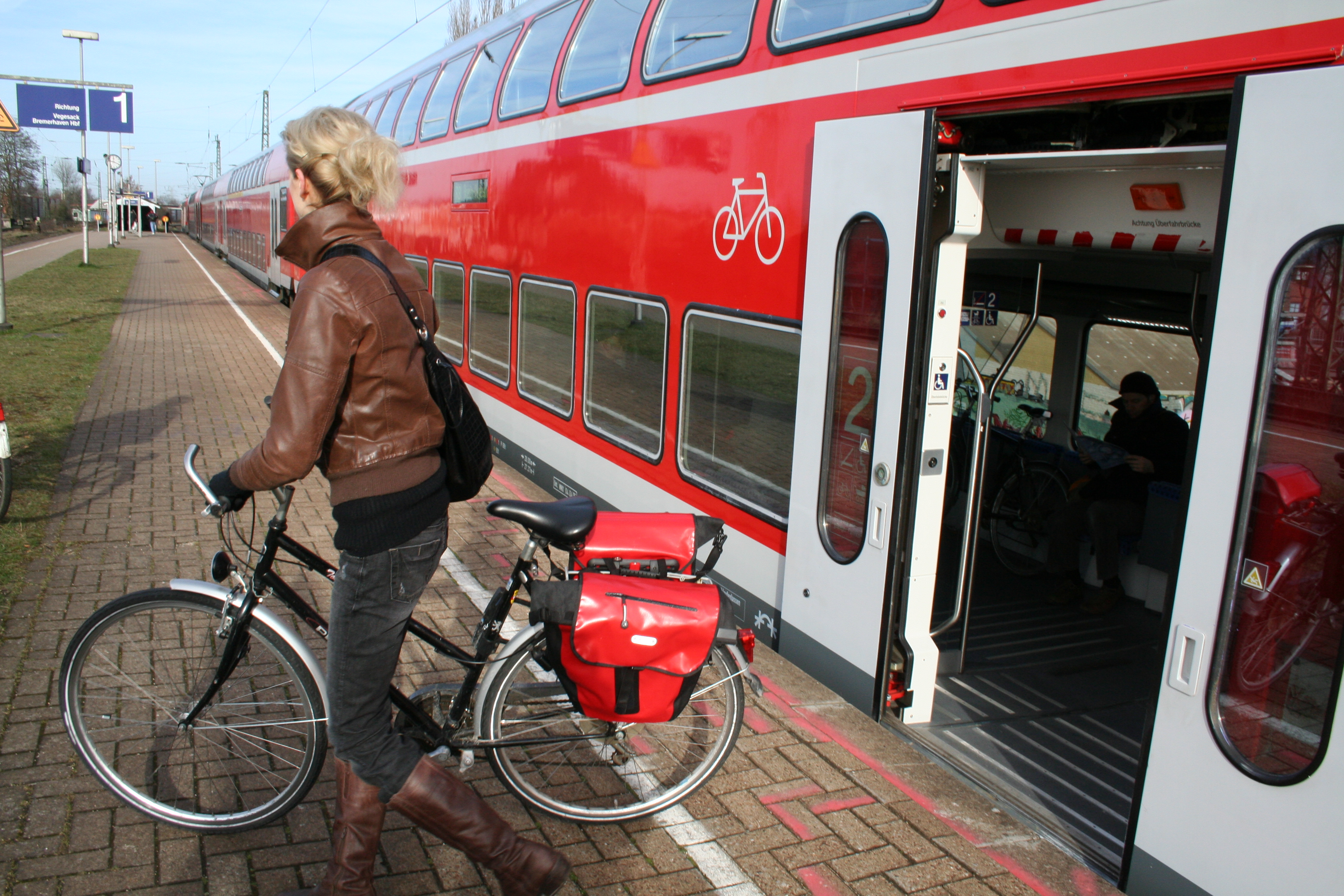 Frau mit Rad steigt aus Regionalzug