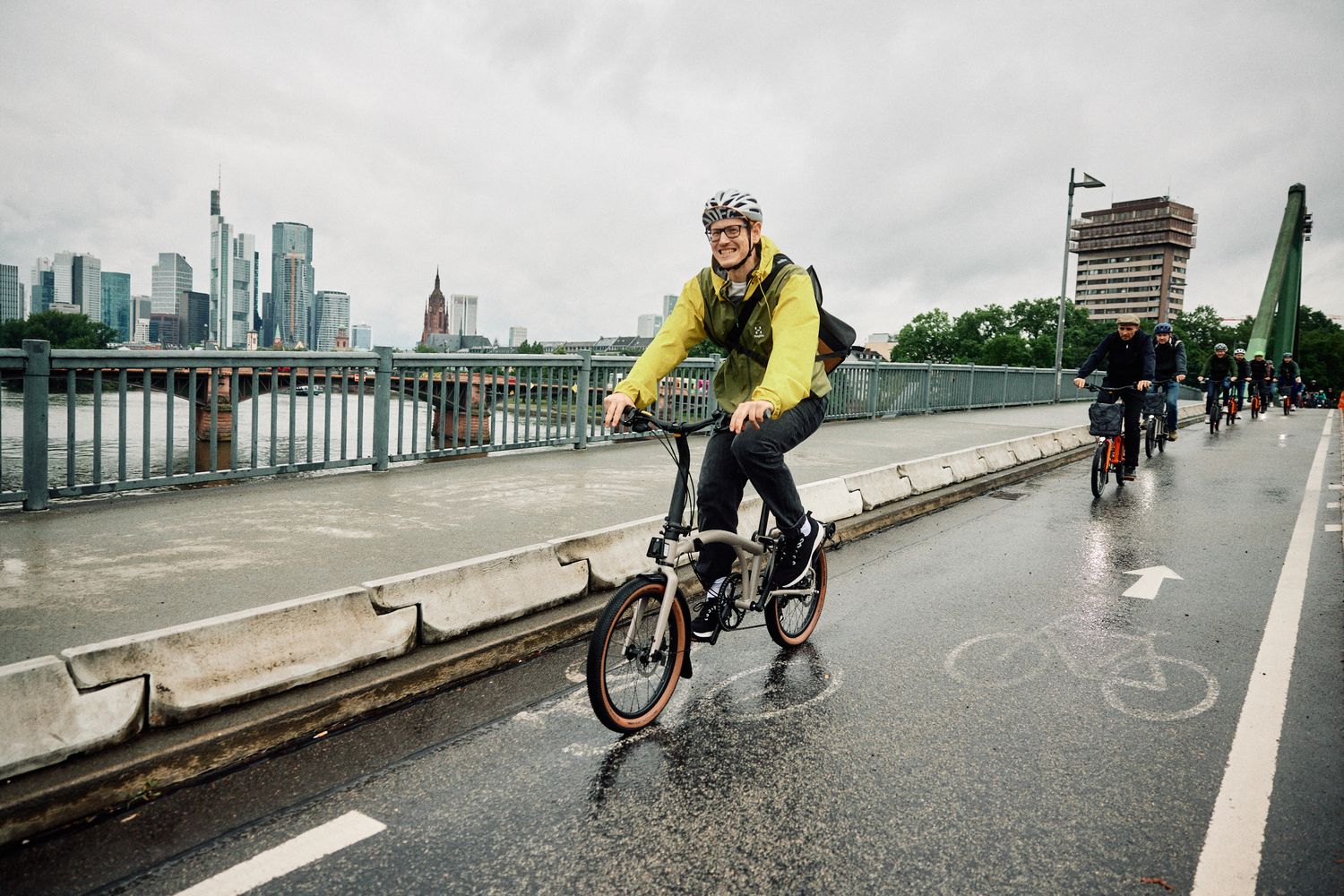Radfahrer auf einem Brompton G-Line bei regenerischem Wetter in der Stadt. 