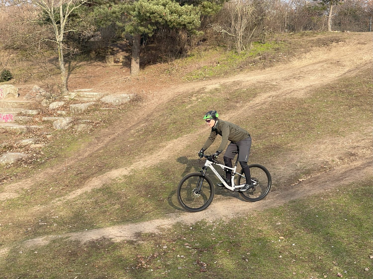 Mountainbiker auf einer Abfahrt im Gelände bei sonnigem Winterwetter. 